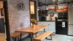 Una cucina con parete in mattoni, soffitto in legno e zona pranzo con tavolo e panche.