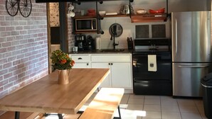 Una cucina moderna con soffitto in legno, televisione a schermo piatto, tavolo con panche e frigorifero.