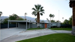 Une maison moderne dotée d’un garage fermé, d’une pelouse bien entretenue et d’un palmier.