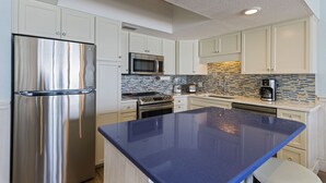 Een moderne keuken met witte kasten, roestvrijstalen apparatuur en een blauw eiland.