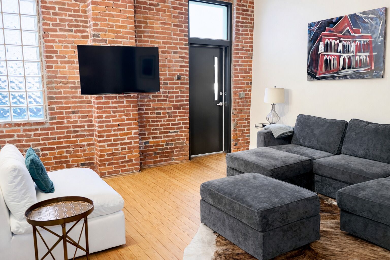 Una sala de estar con pared de ladrillo, un televisor de pantalla plana, un sofá y un cuadro.