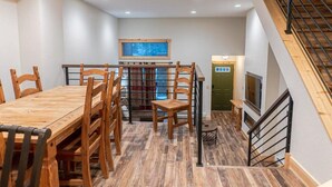 A dining area with a wooden table and chairs, a staircase, and a view of a window with curtains. - Walk to Skiing, Hiking and Main Street! (Breckenridge)