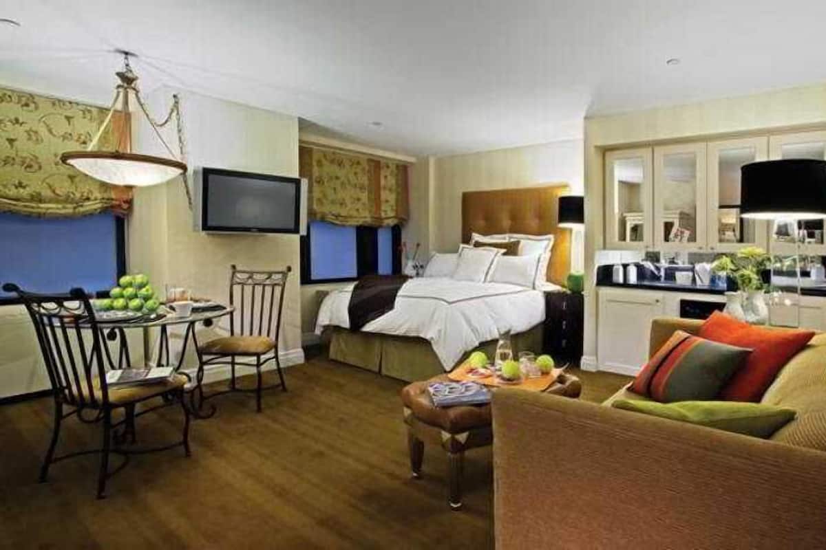 Une chambre d’hôtel comprenant un lit, une table à manger avec des chaises, un coin cuisine et un téléviseur.