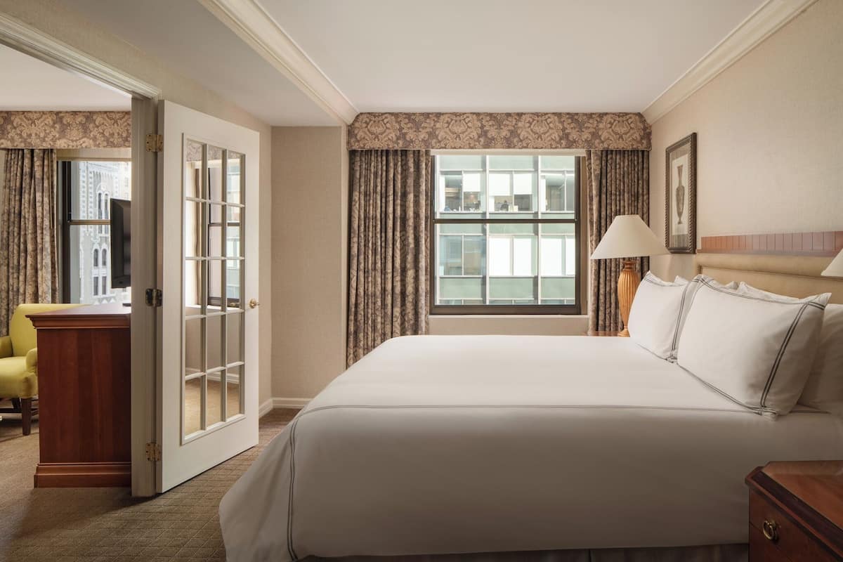 Une chambre d’hôtel avec un grand lit, un bureau, une chaise et une fenêtre avec des rideaux.