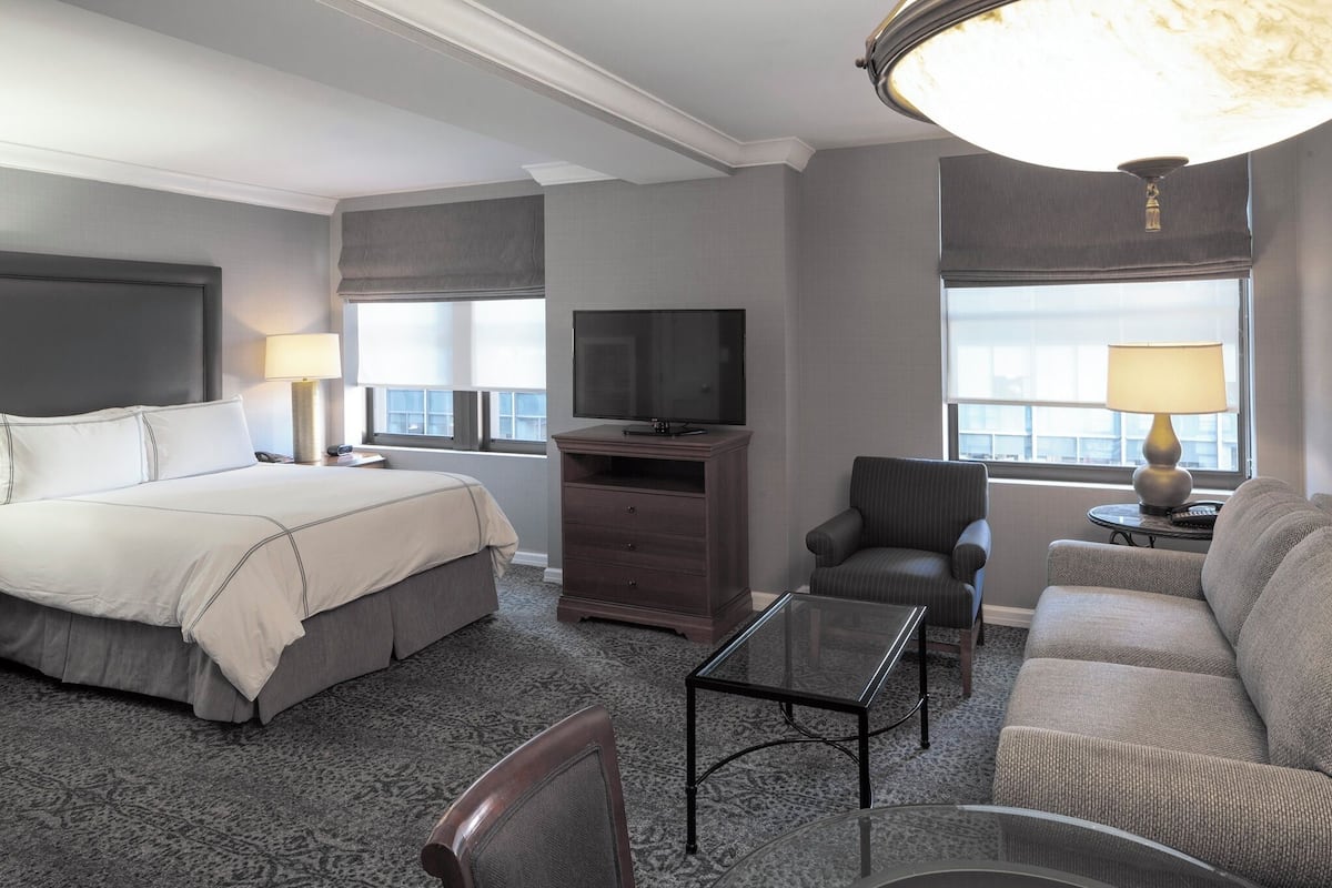 Une chambre d’hôtel équipée d’un lit, d’une télévision, d’un canapé, d’une chaise et d’une table.