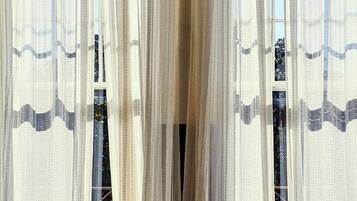 A room with sheer curtains, a hanging light fixture, and a view through the window.