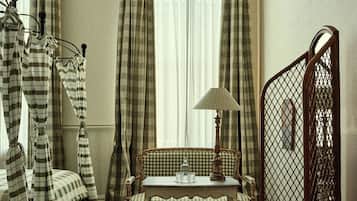 Una habitación con un sofá a cuadros, una mesa con una lámpara y una cama con cortinas a rayas.