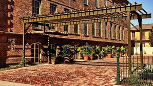 A brick building with a covered walkway and potted plants. - Hotel Peter and Paul, an Ash Hotel (New Orleans)