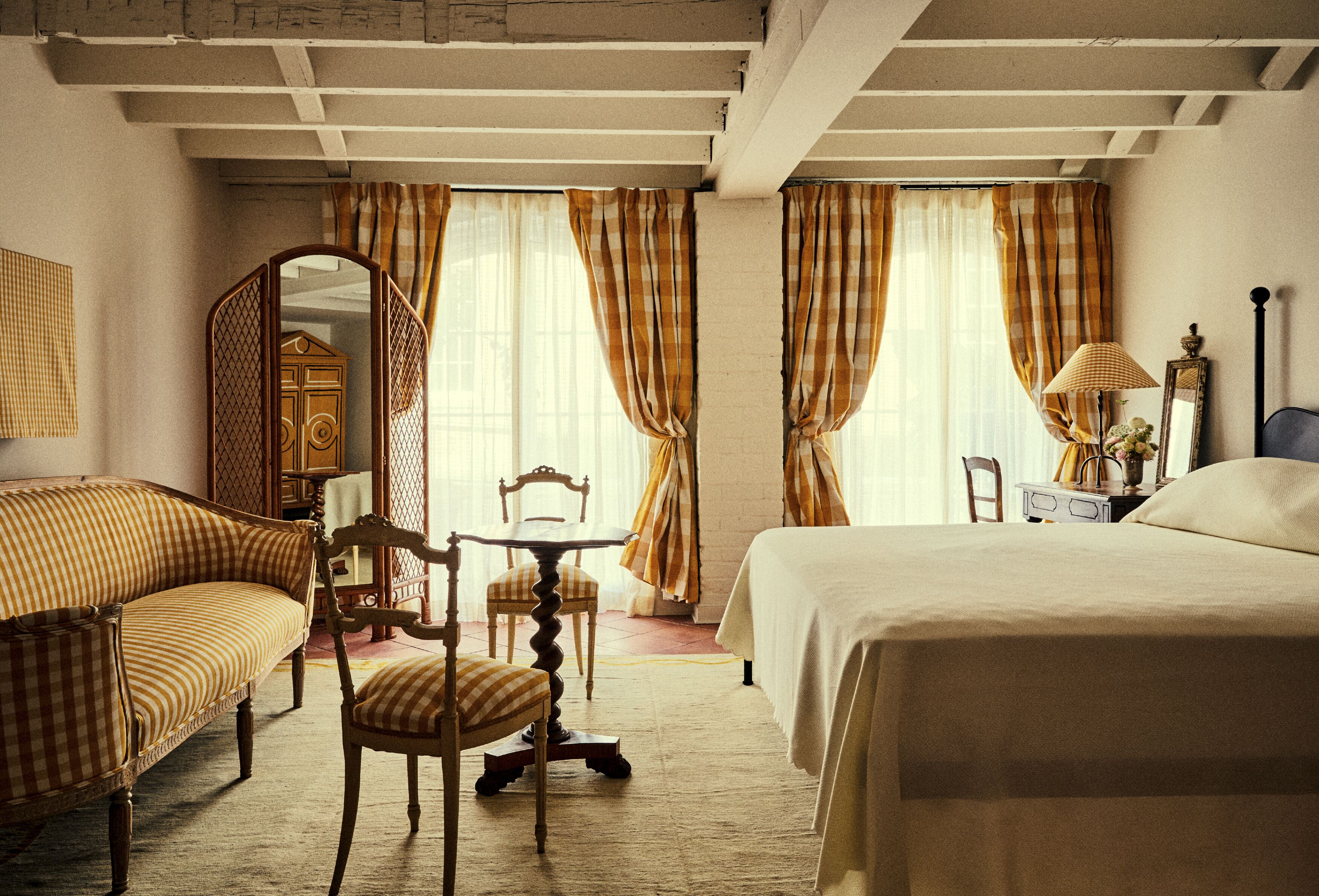 Een klassieke kamer met een bed, een bank, een stoel, een tafel en een spiegel.