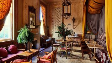 Una habitación de estilo antiguo con una mesa de madera, sillas, un sofá y un tablero de ajedrez.