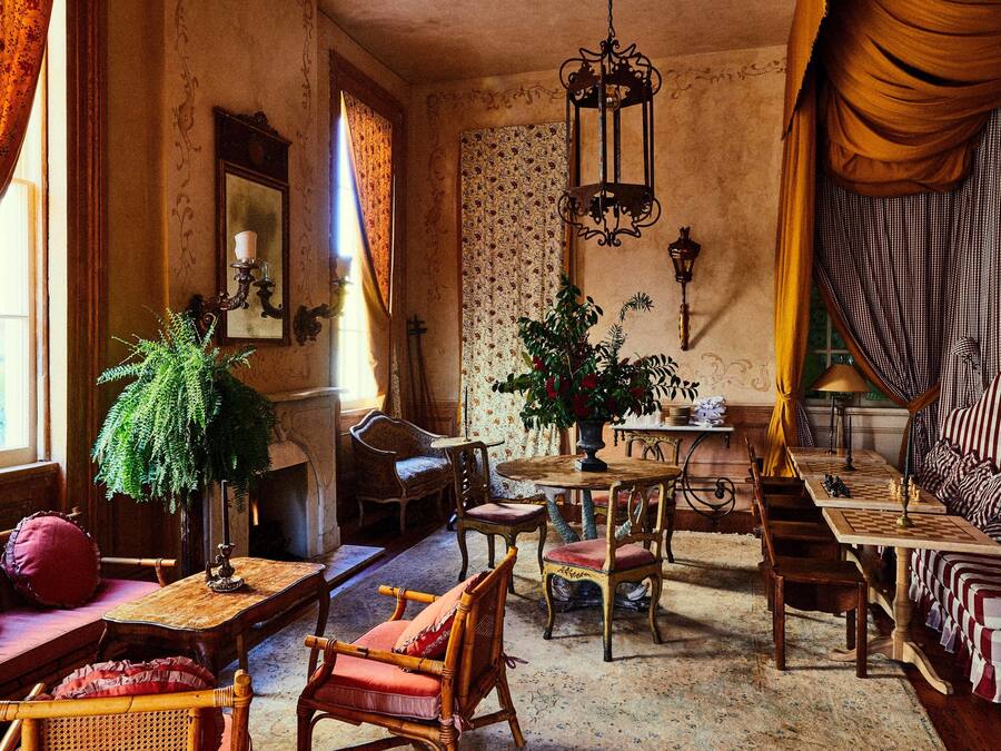 Una habitación de estilo antiguo con una mesa de madera, sillas, un sofá y un tablero de ajedrez.
