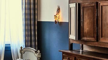 A bedroom with a checkered bedspread, a wooden dresser, and a hanging light fixture.
