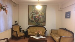 Un salon avec deux canapés, une table basse et un tableau représentant des fleurs accroché au mur.
