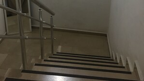 Un escalier avec des rampes en métal et, sur le mur, une fresque représentant un paysage urbain.