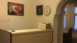 Une pièce comprenant un bureau, une horloge, un tableau encadré et une fenêtre avec des rideaux.