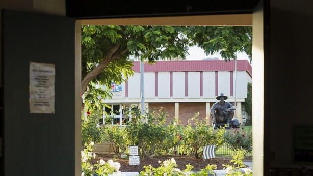 An exit sign, a building with a red roof, and a garden with flowers and chairs. - Hotel Cunnamulla (Cunnamulla)