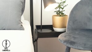 A modern hotel room with a bed, a nightstand with a lamp, a potted plant, and a chair. - Hotel Cunnamulla (Cunnamulla)