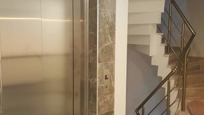 An elevator with a marble finish, a staircase with metal railings, and a tiled floor. - Taksim Soushian Hotel (Istanbul)