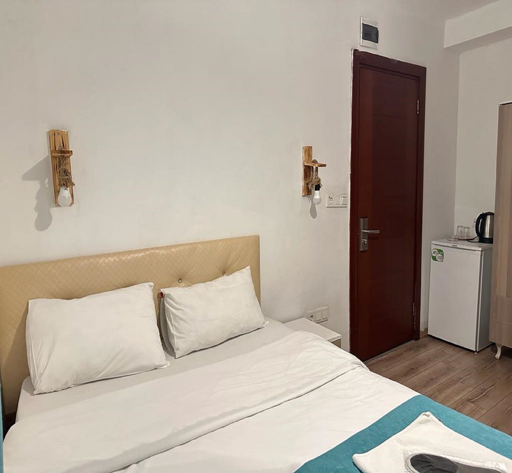 A hotel room with a bed, a small kitchenette, and a door.