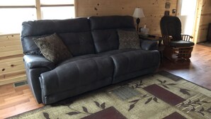 Un salon chaleureux avec un canapé en cuir foncé, un tapis à motifs et des murs en bois.