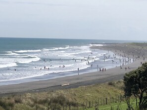 A beach with waves, people, and a fence.