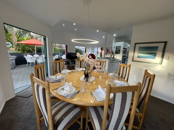 A dining area with a round table, striped chairs, and a chandelier.