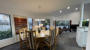 Comedor con una mesa redonda dispuesta para seis personas, rodeada de sillas de madera. Hay un ventanal grande que ofrece vistas al exterior.