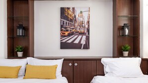 Une chambre d’hôtel avec deux lits, un tableau représentant un paysage urbain accroché au mur et de petites plantes en pot.