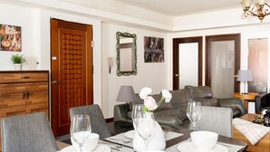 Un coin repas avec une table dressée pour quatre personnes, un canapé, un miroir et une porte.