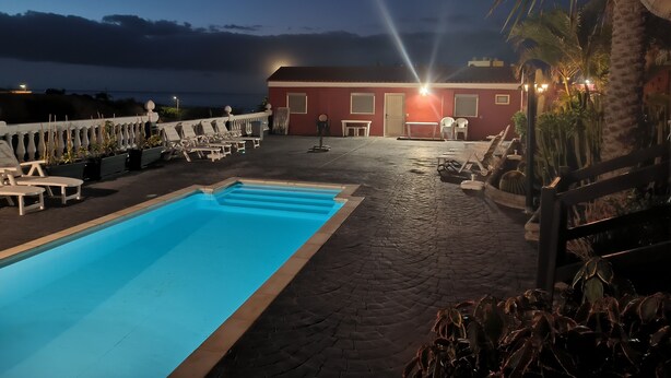 A rooftop pool area with lounge chairs, a pool, and a building with a red facade. - Historical house facing the sea in Finca de Plataneras. (San Andrés)
