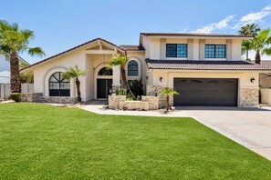 Une maison à deux étages avec un garage, une pelouse bien entretenue et des palmiers.