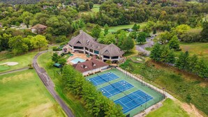 A golf course with a tennis court, a swimming pool, and a large building with a unique roof. - Close to Outdoor Pool, Jetted Tub, Rustic Lodge! (Reeds Spring)