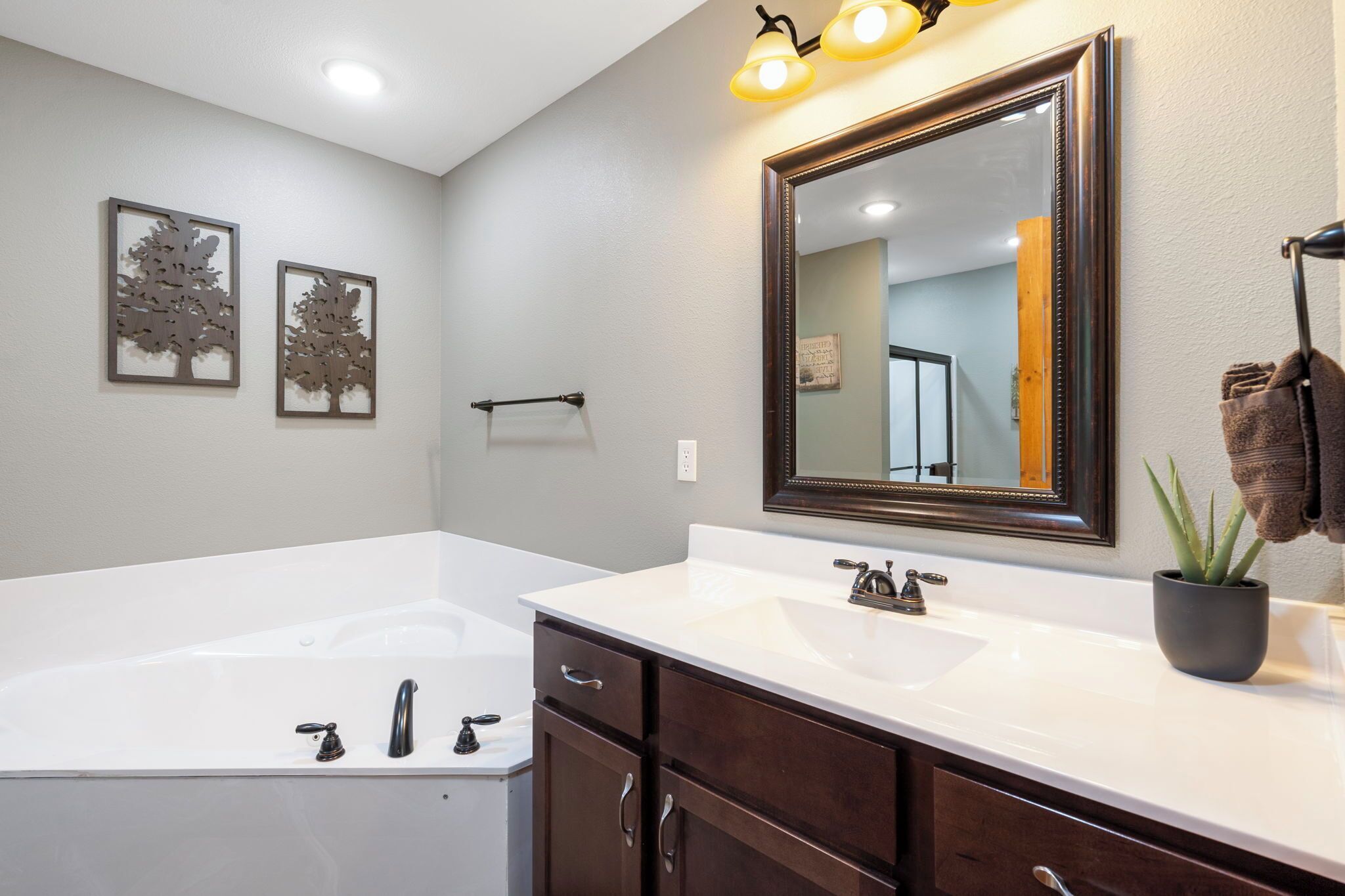 Une salle de bain avec une grande baignoire, deux lavabos, un miroir et des luminaires fixés au mur.