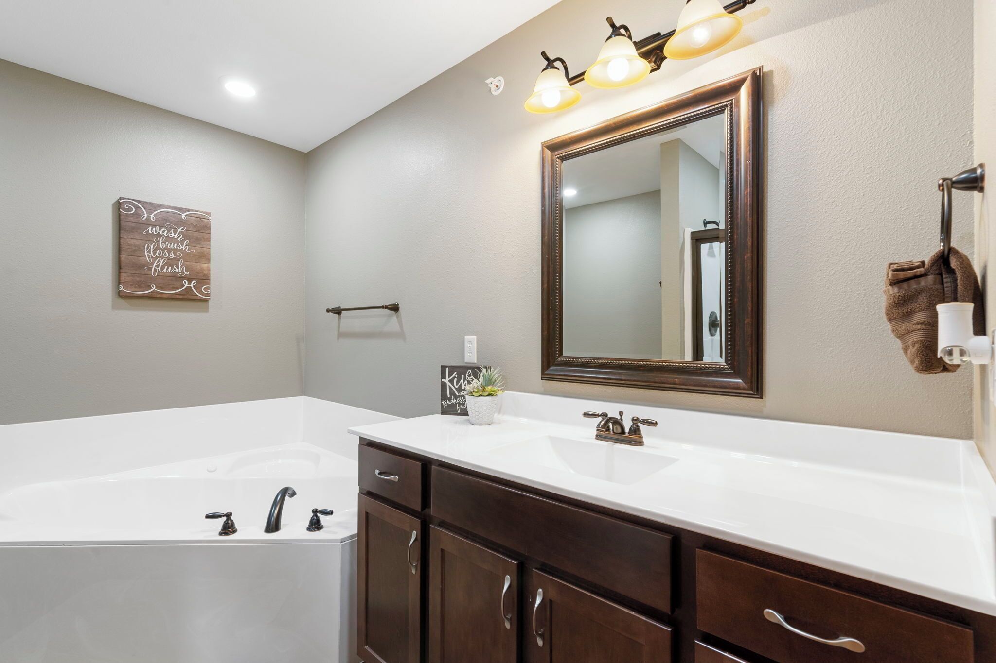 Une salle de bain avec un grand miroir, deux lavabos, une baignoire et un porte-serviettes.