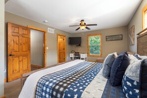A bedroom with a bed, a desk, a television, and a window with a view of trees. - Close to Outdoor Pool, Jetted Tub, Rustic Lodge! (Reeds Spring)