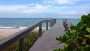 A wooden boardwalk leading to a beach with a clear view of the ocean and sky. - Beachcomber Bungalow: Slow Down, East of A1A, Heated Pool, Hot Tub & Beach Gear (Vero Beach)
