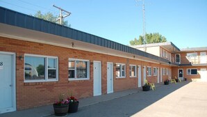 A motel with numbered rooms, a parking lot, and potted plants.