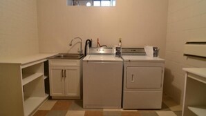 A compact laundry room with a washing machine, dryer, and sink.