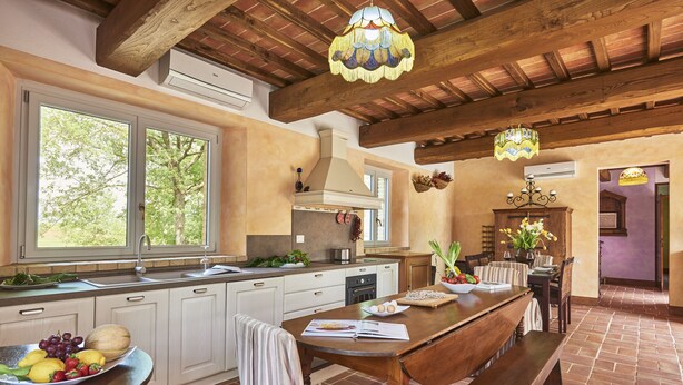 A kitchen with a wooden table, a bench, and a fruit bowl.