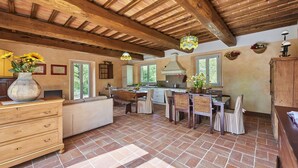 A spacious kitchen with a large island, wooden ceiling beams, and ample natural light from windows.