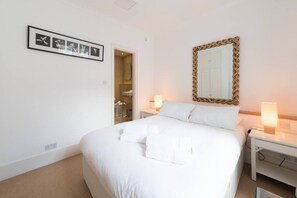 Une chambre d’hôtel avec un lit, des lampes de chevet, un miroir et un tableau encadré au mur.