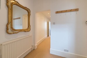 Un couloir avec un grand miroir décoratif, un porte-manteau et un radiateur.