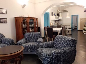 A living room with patterned sofas, a wooden cabinet, and a dining area with a table and chairs. - Apartment in historical building, pedestrian area, full center, 6 beds Wifi (Alassio)