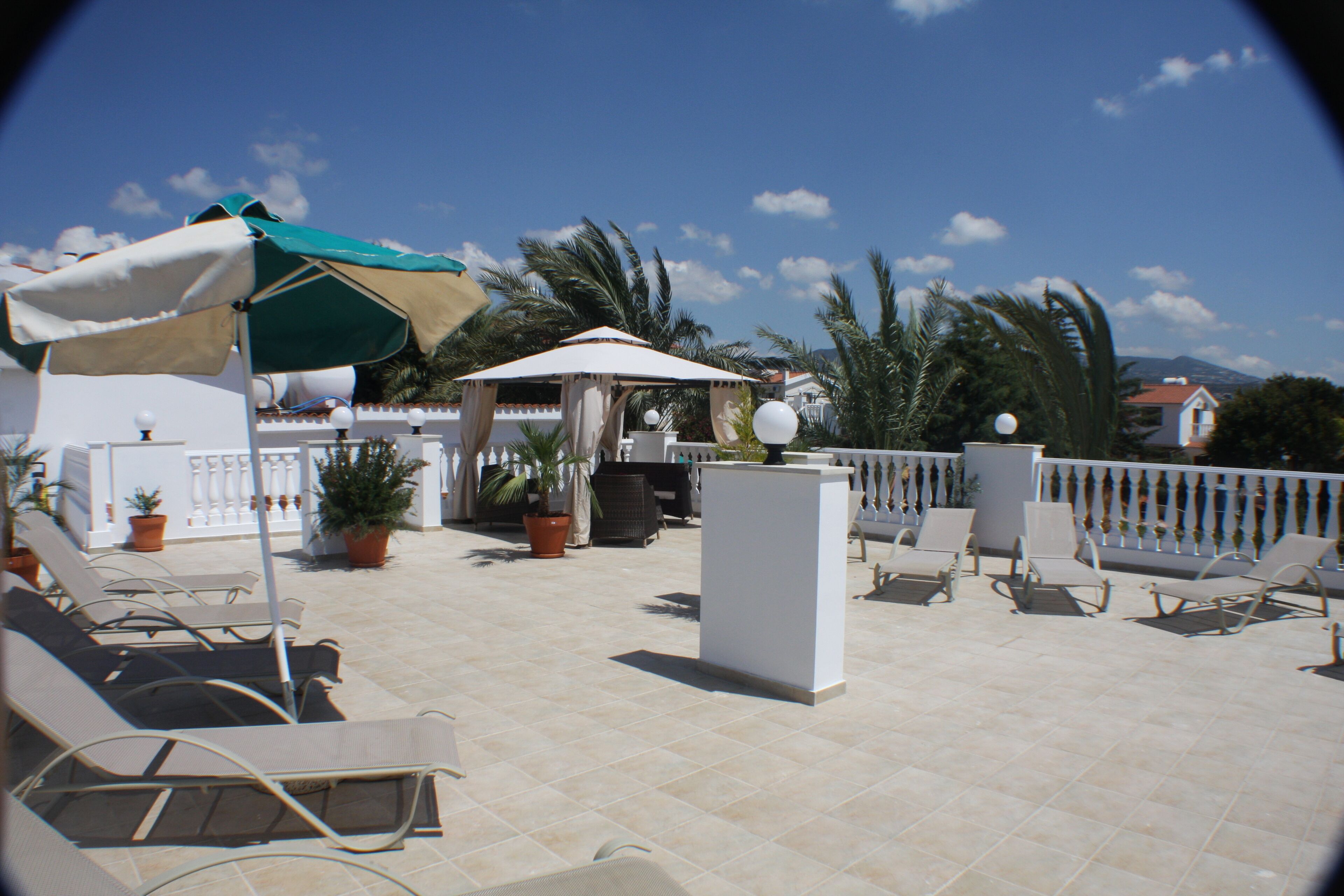 A terrace with lounge chairs, potted plants, and a white column.
