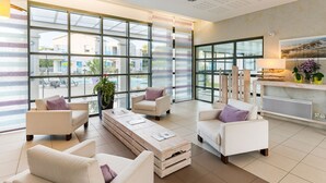 Eine großzügige Lobby mit großen Fenstern, einem Empfangsbereich und Sitzgelegenheiten.