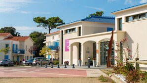Ein Hotel mit moderner Fassade, einem Parkplatz und blauem Himmel.