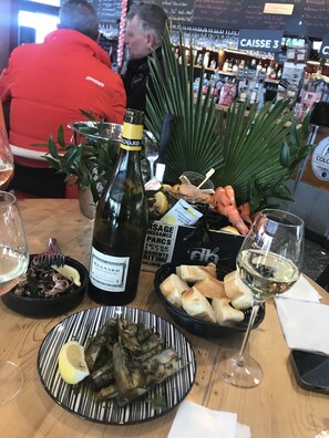Ein Esstisch mit einer Weinflasche, einem Teller Essen und einem Weinglas.
