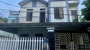 A multi-story building with a white and grey facade, a balcony on the upper floor, and a white fence with decorative balusters. - Tamcoc White Swan Hostel (Nam Hoa Lu)