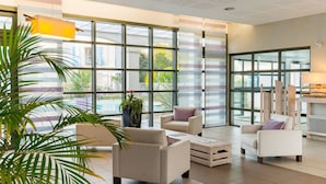 A spacious lobby with large windows, a pool view, and modern furniture.