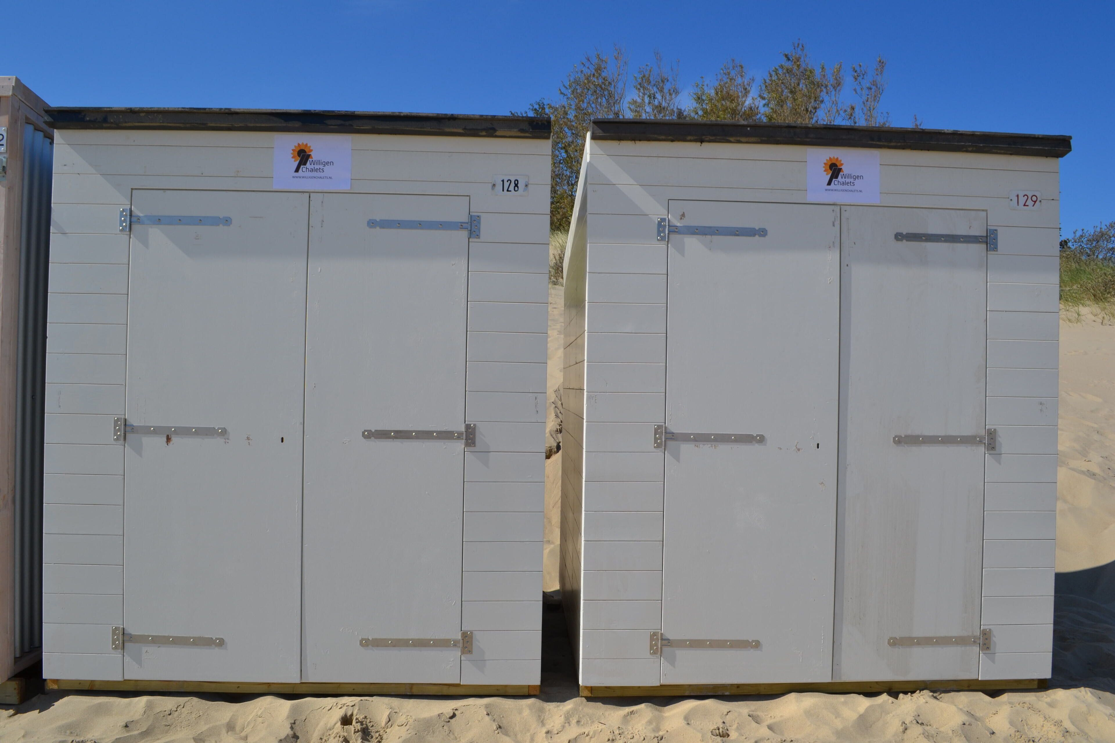 Two identical white portable cabins with metal latches, each marked with a number and a logo.